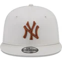 beige-flache-snapback-kappe-mit-braunem-logo-9fifty-league-essential-der-new-york-yankees-mlb-von-new-era